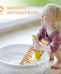 Child using No Sweat Bamboo Washboard For Hand Washing Clothes with grooves and yellow cloth in a sink.