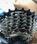 Close-up of 7 Speed Freewheel 14 28 Teeth MF TZ500 Durable Bicycle Gear Cog for smooth shifting on a gloved hand.