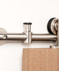 Contemporary Stainless Steel Sliding Barn Door Hardware Kit For Wood Doors Satin Finish 6 Ft Rail 220 Lb Capacity Smooth Quiet Glide Easy Install Made From 304 Grade Steel, close-up view of installation on wooden door