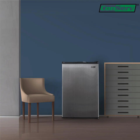 A Top Shelf 3 Cubic Foot Midi Upright Freezer In Stainless Steel With Reversible Door And Adjustable Feet For Basements Or Break Rooms This Sweet Space Saver Delivers Zero Fuss Setup And Drops Heavy Chill Wherever You Park It Today next to a chair.