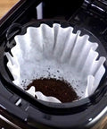 Sleek Black 12 Cup Programmable Drip Coffee Maker With Bold Brew Control auto timer with filter and coffee grounds.
