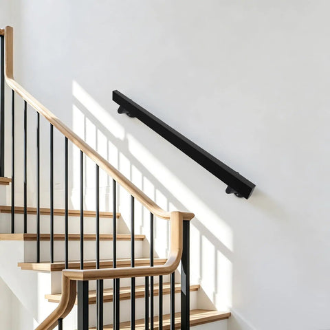 Badass Black Stainless Steel Wall Mount Handrail For Stairs And Hallways With Heavy Duty Support mounted on a wall beside stairs.