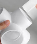 Hands holding five way 2 inch PVC pipe fittings white SCH40 furniture grade connectors set of 4 for DIY projects cubes frames and more
