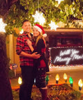 Couple smiling under Christmas lights with Will You Marry Me Neon Light Sign For Wedding Decor And Proposal Night Light Up Letters