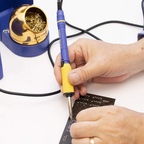 Person using FM2027-01 Soldering Iron With Grip And Heatproof Pad for FX951 FX952 FM203 FM204 FM206 stations on circuit board.