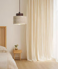 Modern Mini Pendant Light, Travertine Stone Light Fixture with Wooden Accent hanging above a bed in a cozy bedroom.