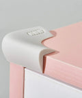 Butter Smooth And Kid Tough Food Grade Silicone Corner Protectors For Baby Proofing Couch And Table Edges on a pink table corner.