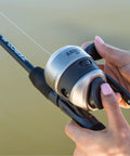 Closeup of hands gripping silver and black Grab And Go Spincast Rod And Reel Combo With A Six Foot Two Piece Fiberglass Rod And Size 30 Reel