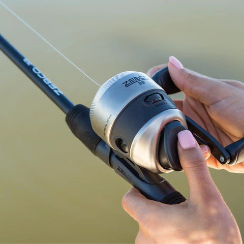 Closeup of hands gripping silver and black Grab And Go Spincast Rod And Reel Combo With A Six Foot Two Piece Fiberglass Rod And Size 30 Reel
