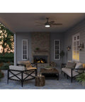Outdoor porch with Burlington Two Light Wall Lantern In Oil Rubbed Bronze Finish illuminating seating area near fireplace.