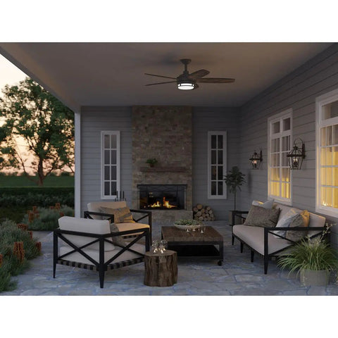 Outdoor porch with Burlington Two Light Wall Lantern In Oil Rubbed Bronze Finish illuminating seating area near fireplace.