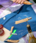 Nomad Camping Kitchen Utensil Kit with corkscrew knife on wine bottle, tomatoes on cutting board, outdoor scene.