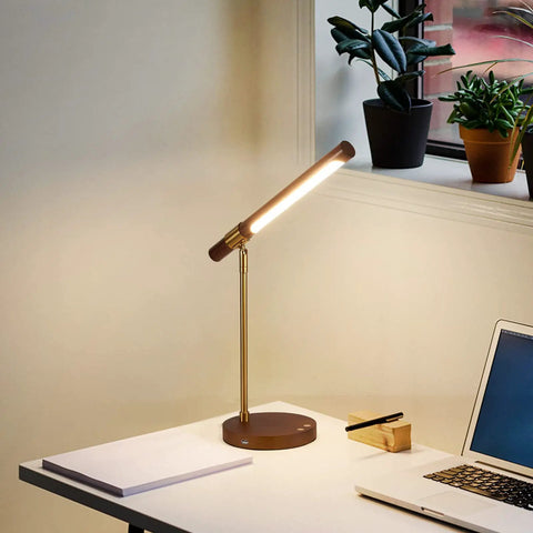 LED Wood Grain Desk Lamp With Wireless Charger And USB Port For Home Office on a desk next to a laptop and plants.