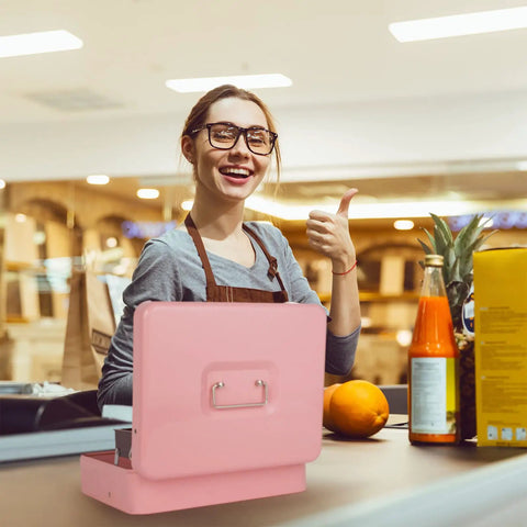 Smiling person using large pink cash box with money tray and key lock for cash till at a market counter