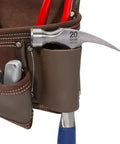 Close-up of heavy duty leather tool apron with seven pockets, tool loops, hammer holder, and rivet reinforced edges for pro grade toughness.