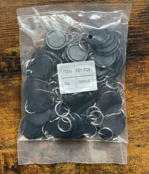 50 Pcs Pack Re-Writable RFID Hotel Key Fobs For 13.56MHz Locks in clear plastic bag on wooden surface