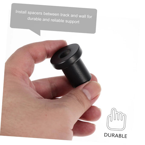 Hand holding a black 4 Pack Carbon Steel Sliding Barn Door Track Spacer used for wall and rail track assemblies.