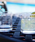 Lab Beaker Rocks Glasses Set Of 2 for cocktails, one glass filled with iced drink and lime, modern laboratory style on table.