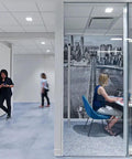 Office workspace with woman working in meeting room, modern decor, glass walls, and cityscape mural