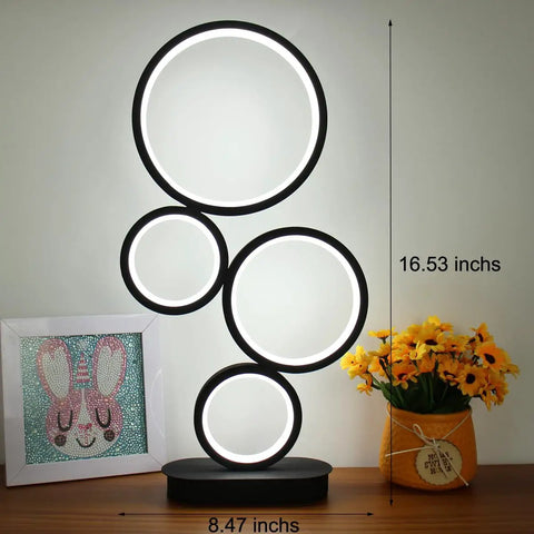 Go To LED Table Lamp For Nightstand And Desk With Dimmable 18W LED And Three Color Temperature Options Modern Circle Design Ideal Bedside Reading Light For Bedroom Living Room Office And Study White Finish, displayed on a table next to flowers and a picture frame.