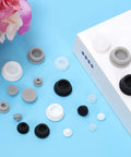 Ultimate 120 Piece Grey Silicone Hole Plug Pack With 9 Sizes For Furniture Legs And Cabinet Doors, Reusable Round Rubber Covers Perfect For Sealing Gaps And Keeping Things Snug On Any Project. Grey, white and black silicone hole plugs in assorted sizes on a blue surface