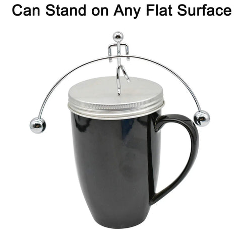 Balance Physics Desk Toy Kinetic Weightlifter Steel Man Figure With Plastic Base demonstrating balance on a black mug