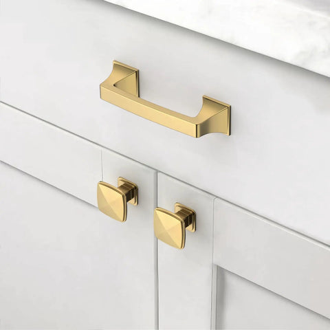 Gold cabinet handle and knobs on white cabinet doors in kitchen.
