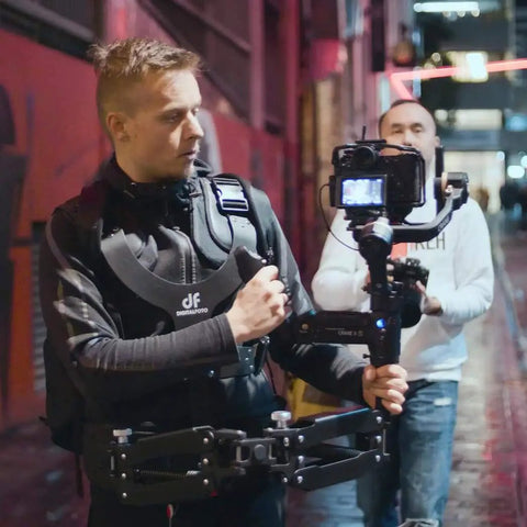 Videographer using Thanos Pro Gimbal Vest Stabilizer System With Adapter Arm For All Day Filming in urban setting