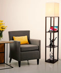Maxwell Charger Shelf Floor Lamp With USB Ports And Electrical Outlet in Havana Brown beside armchair and side table with flowers