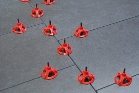 Red tile spacers placed between tiles during installation process