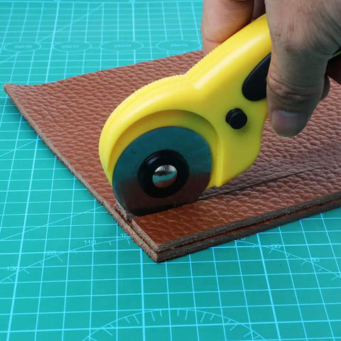 45mm Rotary Cutter Kit With 9 Replacement Blades cutting leather on a green cutting mat