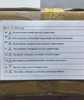 Word of Warning label on a package outlining fragile item handling instructions in multiple languages.