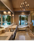 Modern bathroom with freestanding tub, large windows, and elegant lighting showcasing a cozy winter view.