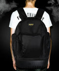 Person wearing black backpack against dark background