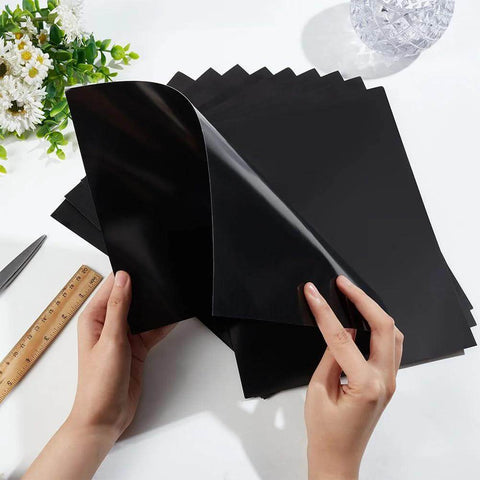 Front view of black BENECREAT laser engraving testing paper sheets, A4 11x8.3 in, double-sided, hands peeling a sheet