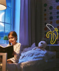 Child reading in room with Banana Neon Sign LED Light 11.4 x 7.9 Inches USB or Battery Powered Wall Decor Night Lamp on wall