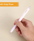 Hand holding a pink Four Cute Retractable Gel Pen With Glitter Cat Design, 0.5mm fine point black ink, showing soft grip feature.