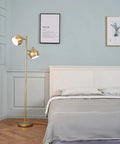 Miles 61 Inch Two Light Floor Lamp in Matte Brass Finish with Adjustable Heads and In Line On Off Foot Switch beside bed