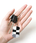 Heavy Duty Aluminum Keychain With Black And White Piano Plate Grid Print Rectangular Steel Keyring Built Tight For Everyday Carry Clean Aesthetic Daily Driver Gift Ready in hand with car keys.