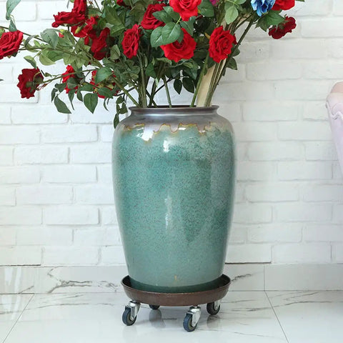 Big Boy Rolling Plant Dolly With Lockable Casters For Smooth Riding Indoors Or Outdoors, Built Like A Tank At Four Hundred Twenty Lb Capacity, Thickened Steel Pan With No Cutouts, Fits Twelve To Fifteen Inch Pots, Pack Of Two supporting a large ceramic pot filled with flowers.