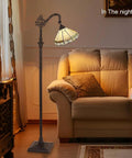 Tiffany Style Stained Glass Floor Lamp 62 Inch Tall With Adjustable Arched Shade Soft Warm Light Antique Cream Finish beside sofa