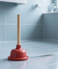 Eighteen Inch Heavy Duty Toilet Plunger Featuring A Thick Red Rubber Cup And Sturdy Wood Grip standing on a tiled bathroom floor.