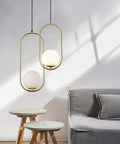 Modern One Light Globe Pendant With White Milk Glass Shade In Brushed Brass Finish For Kitchen Island Farmhouse Living Spaces Mid Century Style Ceiling Lighting Fixture, shown in a living room setting.