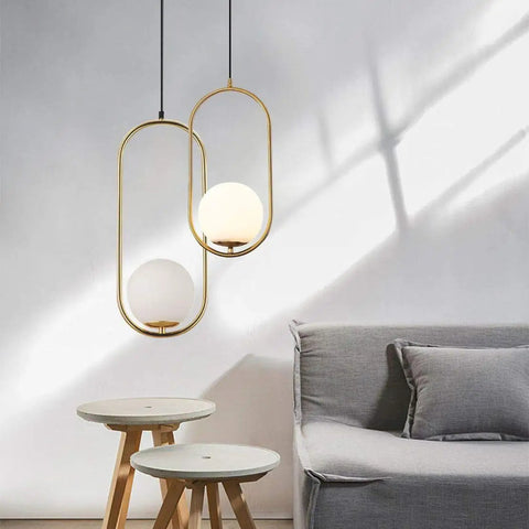 Modern One Light Globe Pendant With White Milk Glass Shade In Brushed Brass Finish For Kitchen Island Farmhouse Living Spaces Mid Century Style Ceiling Lighting Fixture, shown in a living room setting.