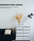 White dresser with 5 Pack Golden Cabinet Pull Handles Single Hole T Bar Style For Cabinets Wardrobe Doors Drawers Kitchen Cupboards Easy Install Hardware Modern Furniture Pulls With Dope Look And Durable Build next to black sofa.
