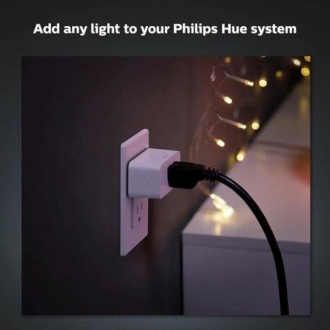 Hue Smart Plug Turns Any Lamp Into a Smart Light with no fuss, plugged into a wall outlet with lights in the background.