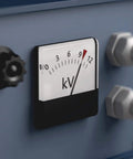 Close-up of a voltmeter showing a reading, mounted on a blue panel with knobs and fasteners.