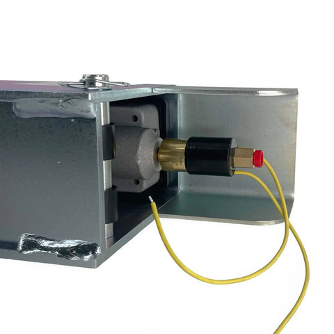 Demco hydraulic surge brake actuator mounted in metal housing; brass piston, black cap, yellow solenoid wires