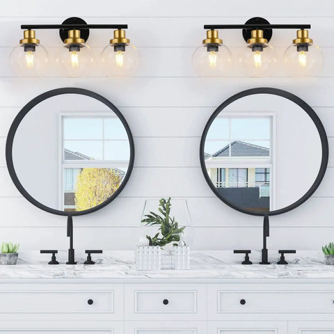 Three Light Bathroom Vanity Light With Clear Globe Shade, Black And Brass Modern Wall Sconces Over Mirror in bathroom setting