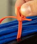 Person using Heavy Duty Reusable Cable Ties With No Sweat Quick Release Lever on blue cables for secure wiring control.